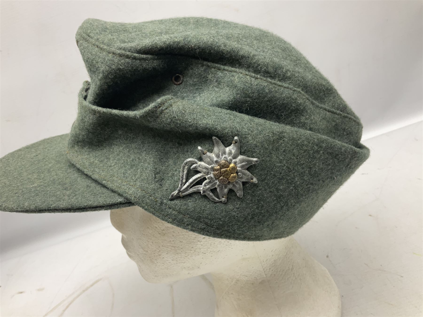 WW2 German Army M43 field cap with triangular cloth eagle and roundel badge and metal edelweiss badge for mountain troops; faintly stamped '5 VMF(?)'