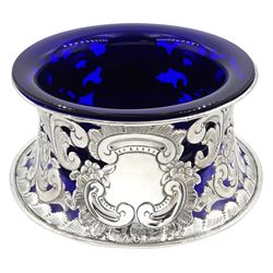 Edwardian silver dish ring in the Irish manner, of circular waisted form, embossed and pierced throughout with flower heads and foliate and C scrolls, hallmarked I S Greenberg & Co, Birmingham 1904, with accompanying blue glass liner, upper rim D17.5cm, approximate weight 6.84 ozt (213 grams)