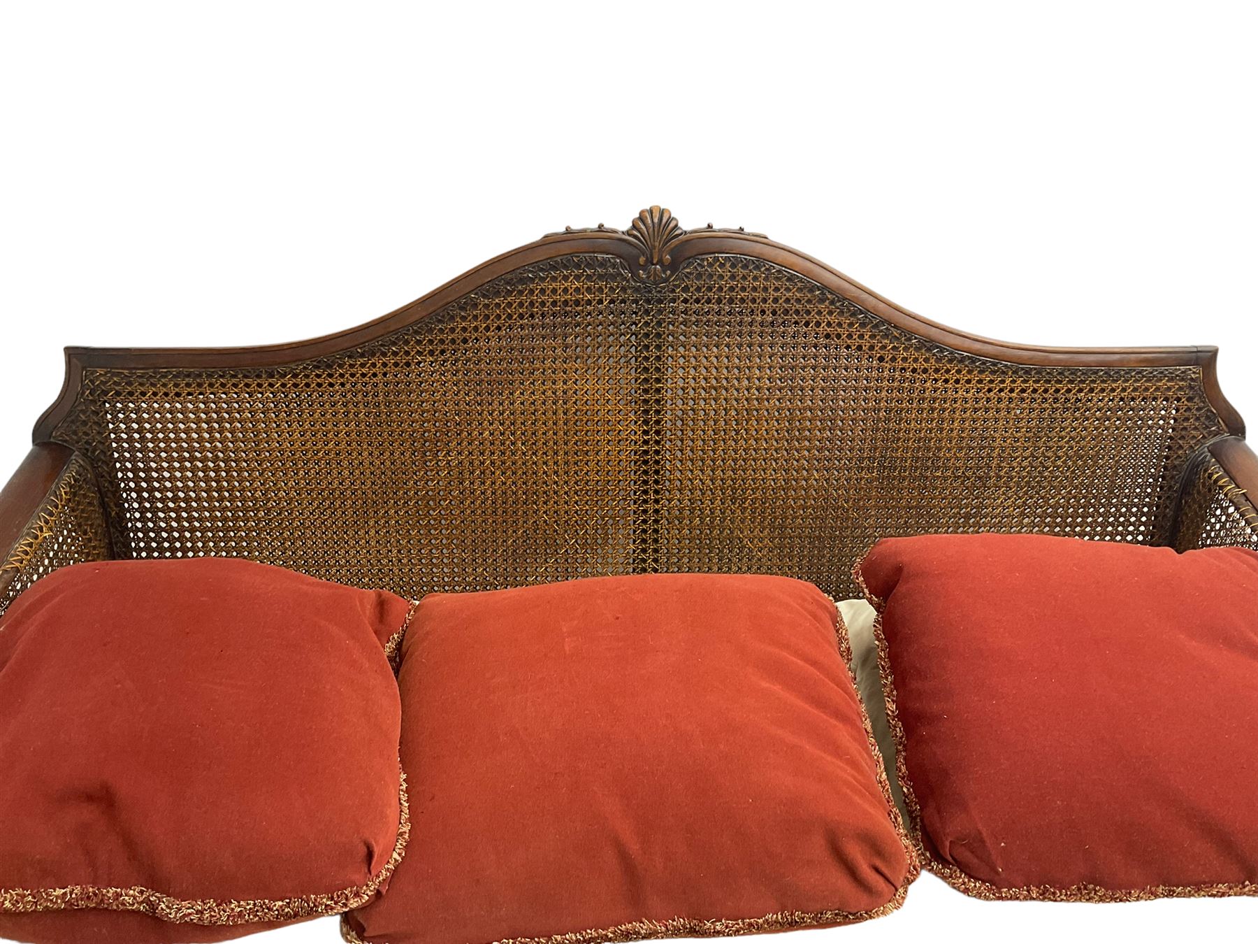 Early 20th century bergère three seat settee, shaped shell carved cresting rail, double caned back and sides, scrolled upright arms and shaped apron carved with shell and foliage, on hairy paw carved feet
