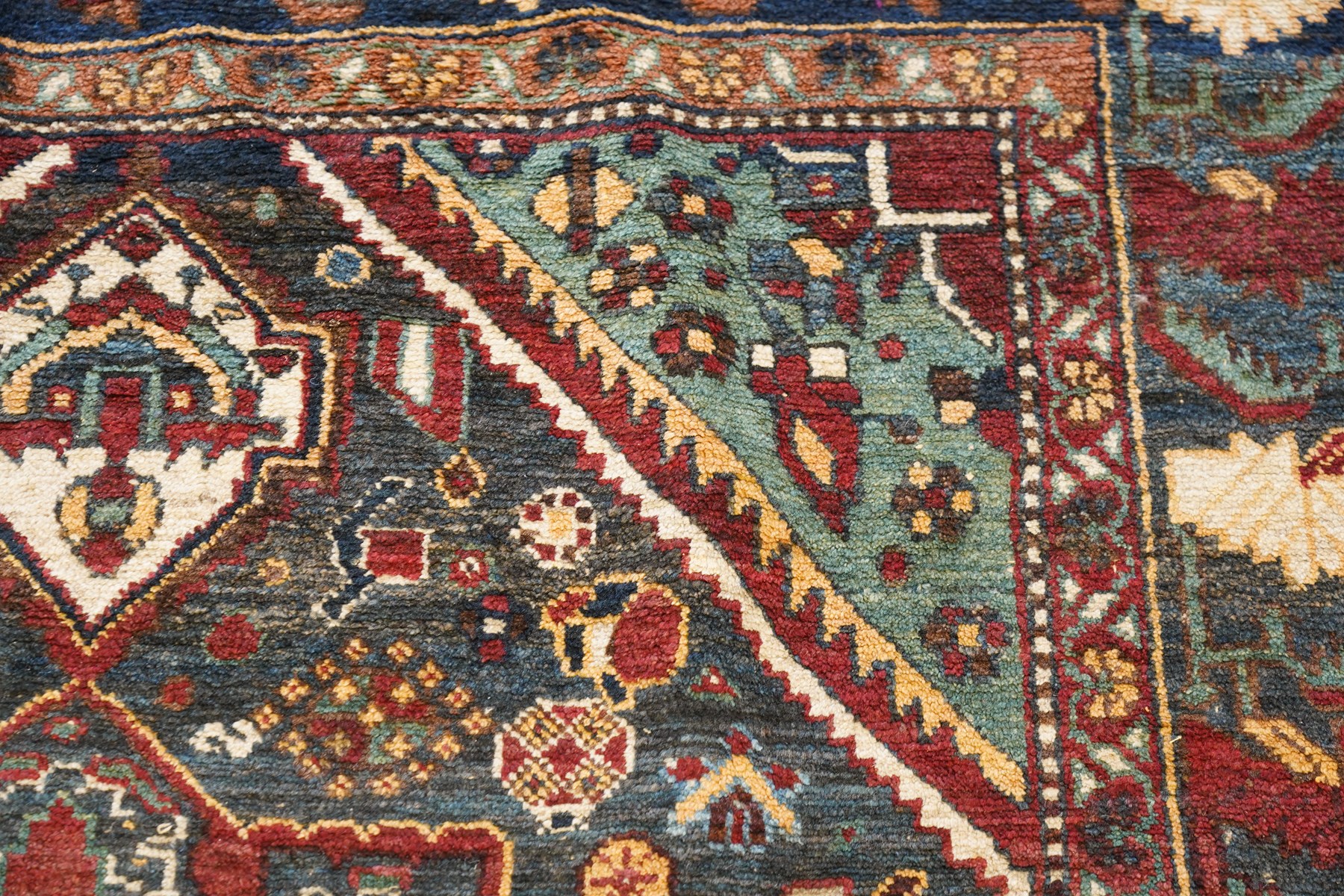 Antique Persian Qashqai dark indigo ground tribal rug, the busy field decorated with a geometric triple pole medallion surrounded by numerous stylised plant motifs with contrasting cyan spandrels, the multiple guard bands woven with stylised palmettes and foliage