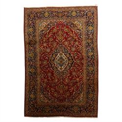 Central Persian Kashan hand-knotted carpet, crimson red field with a central shaped palmet...