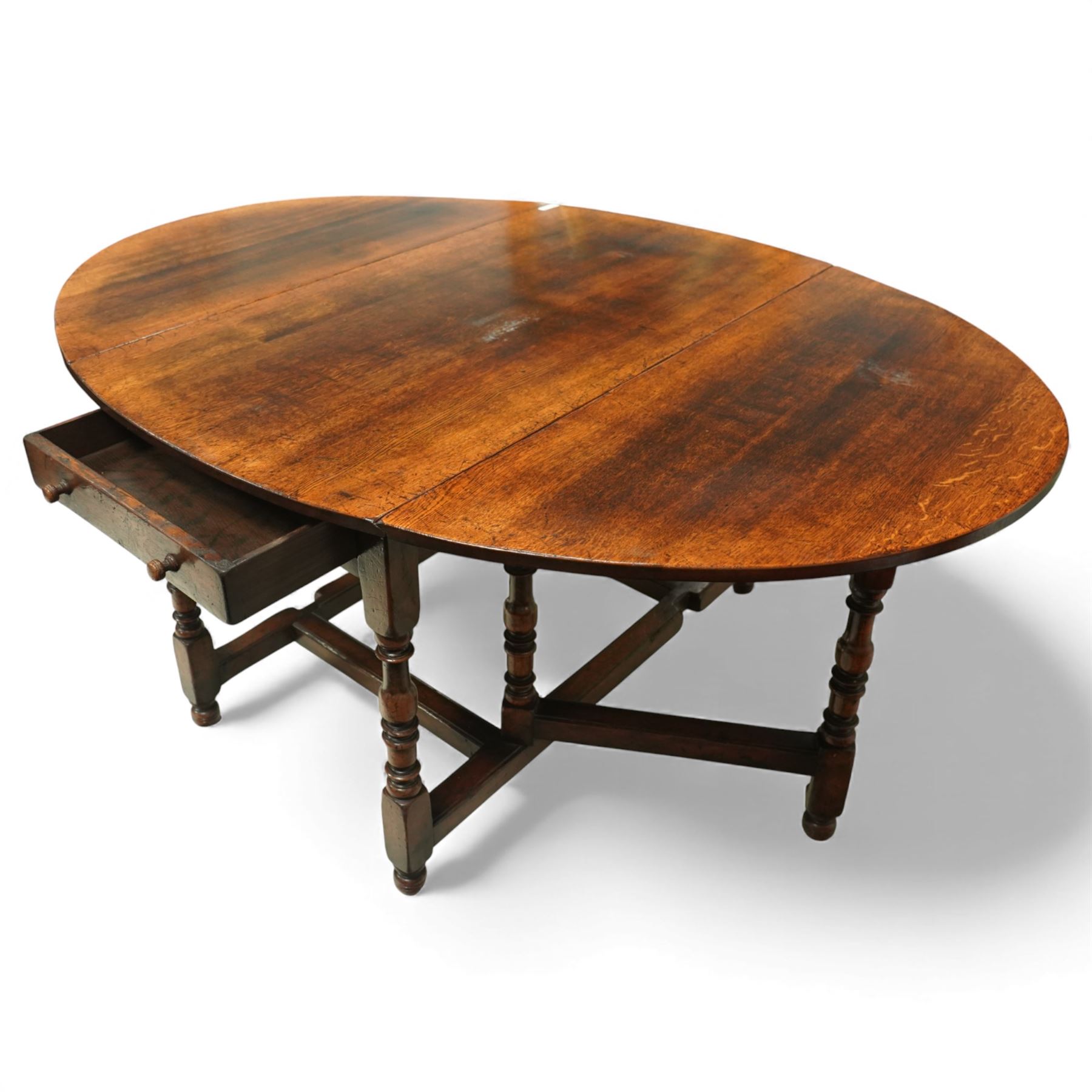 Large 18th century design oak drop-leaf dining table, oval top with twin hinged drop leaves, drawers to either end, raised on turned supports united by an H-stretcher base