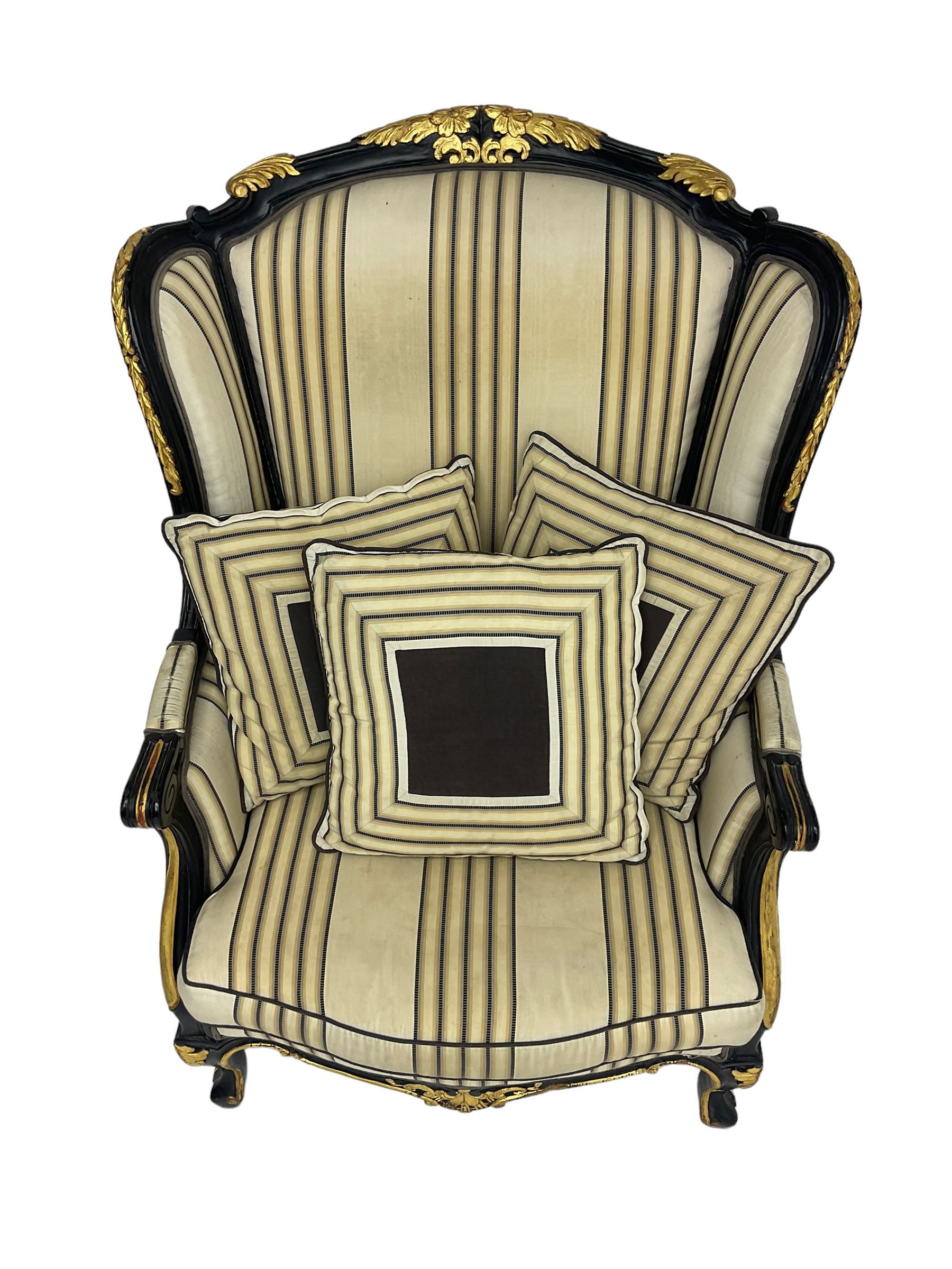 Thomas Messel - Georgian style ebonised and gilt wingback armchair, upholstered in striped fabric, on cabriole front feet