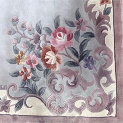 Chinese Aubusson-style jade green wool rug, with a floral medallion and floral corner sprays with a scrolling acanthus and ribbon border in tones of teal, cream, pink, mauve, and cotton fringe ends