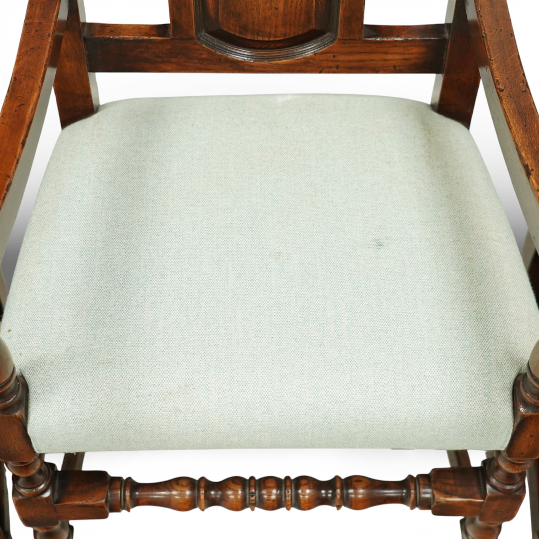 Country House oak high back dining chairs, set of ten comprising eight side chairs and two carvers, each with arched top rail flanked by turned finials over a central fielded panel back, with overstuffed seats upholstered in pale fabric, raised on turned front supports united by stretchers
