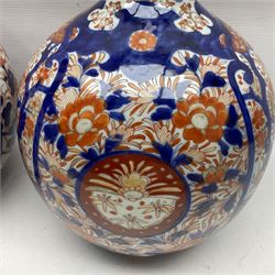 Pair of large 19th century Japanese Imari porcelain bottle vases, painted with shaped reserves of peonies, chrysanthemums and prunus blossom, each H46cm