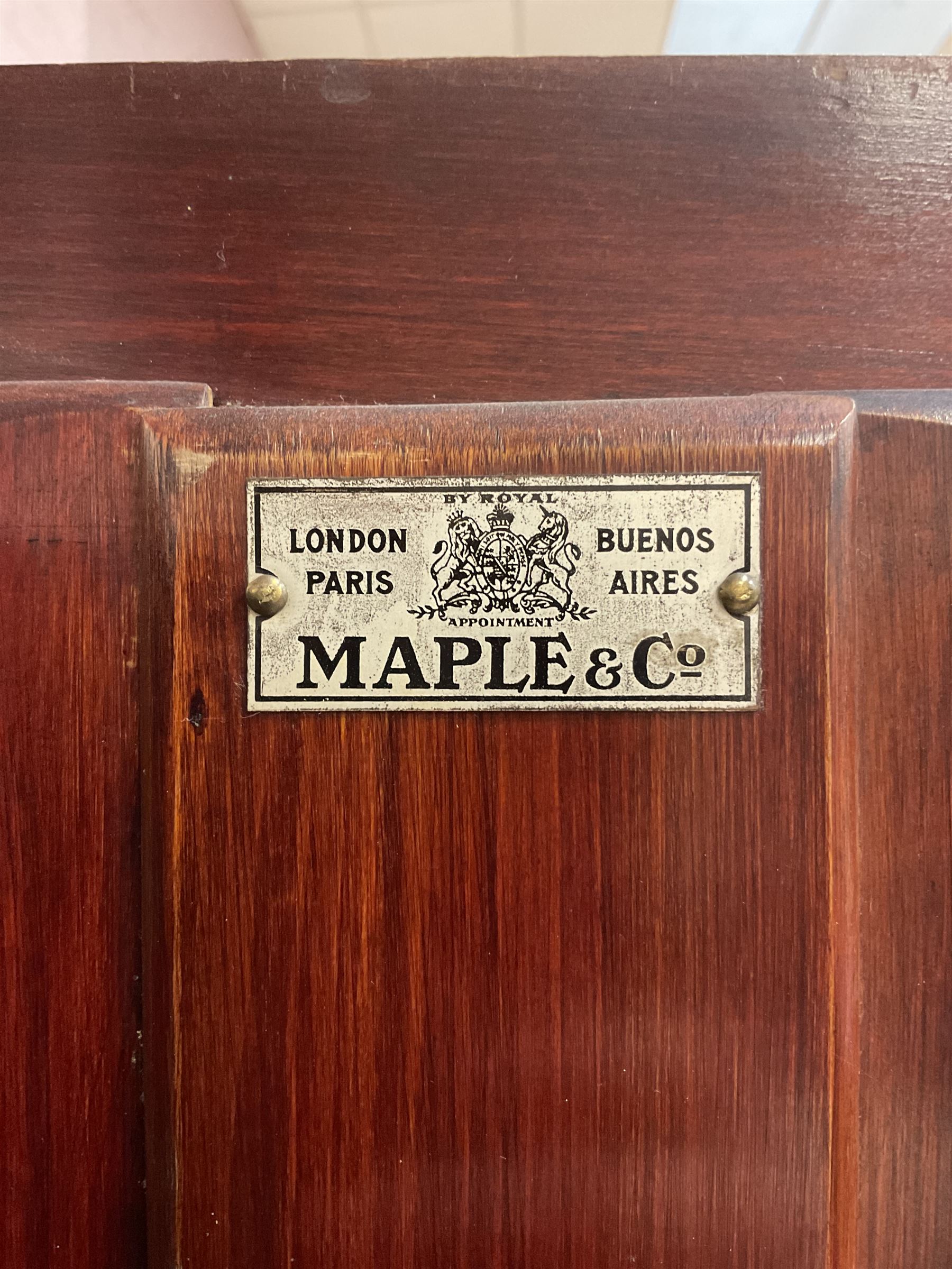Maple and Co - Edwardian Hepplewhite design white painted triple wardrobe, foliate carved projecting cornice over ribbon and husk swag decorated frieze, two curtain lined astragal glazed doors and centre full mirror door, fitted mahogany interior including slides and drawers, plinth base, label to top of central door
