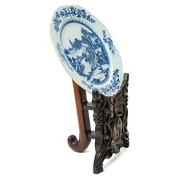 18th century Chinese plate of octagonal design decorated in blue and white with figures by a river with buildings etc W30cm on a 19th century hardwood stand
