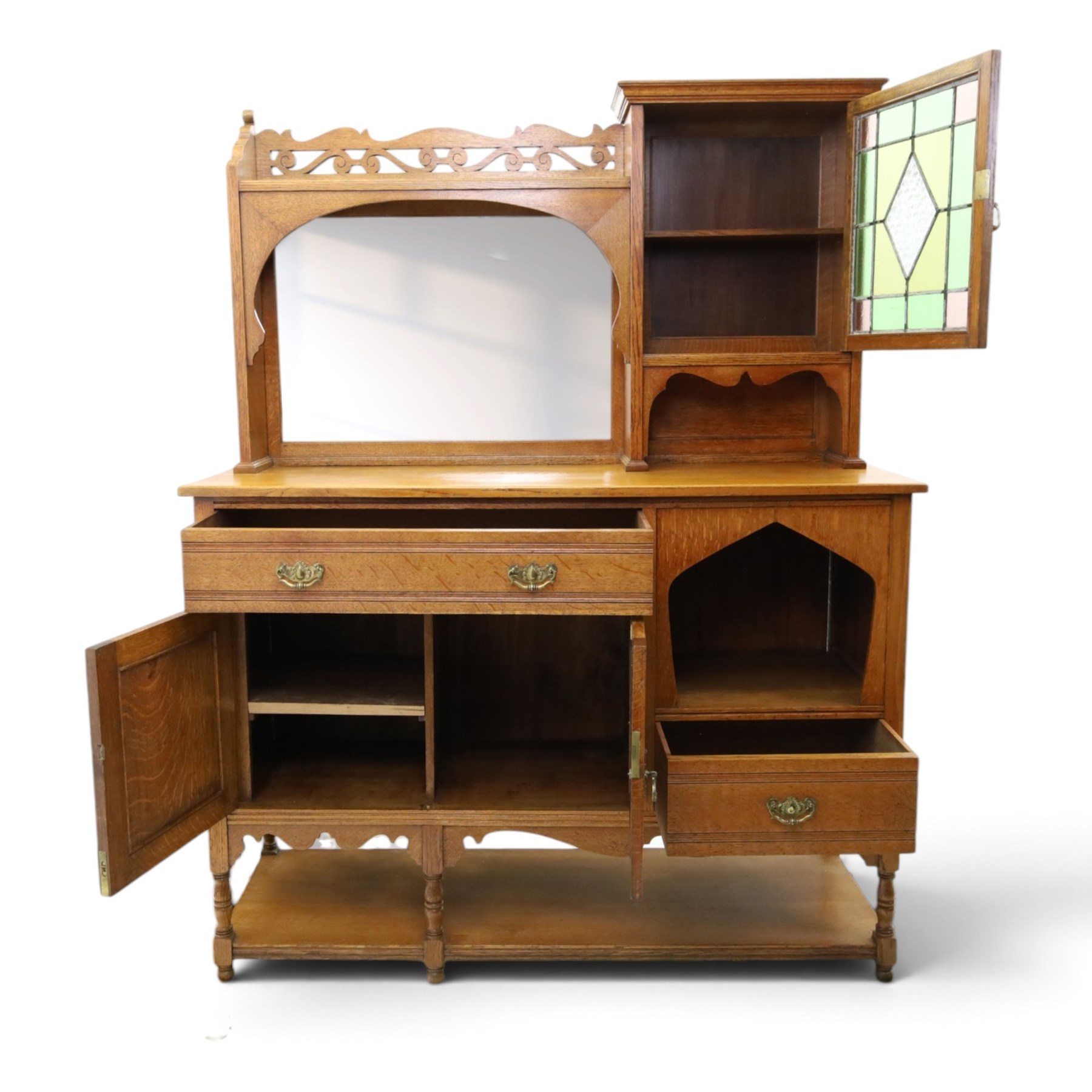 Maple & Co. - Arts & Crafts oak dresser with stained glass cupboard, raised section with pierced pediment above a mirrored back, with a stained glass fronted cupboard with fixed shelf, single long drawer, above a pair of fielded panels, with open recess above a short drawer, raised above a full length undertier with turned supports