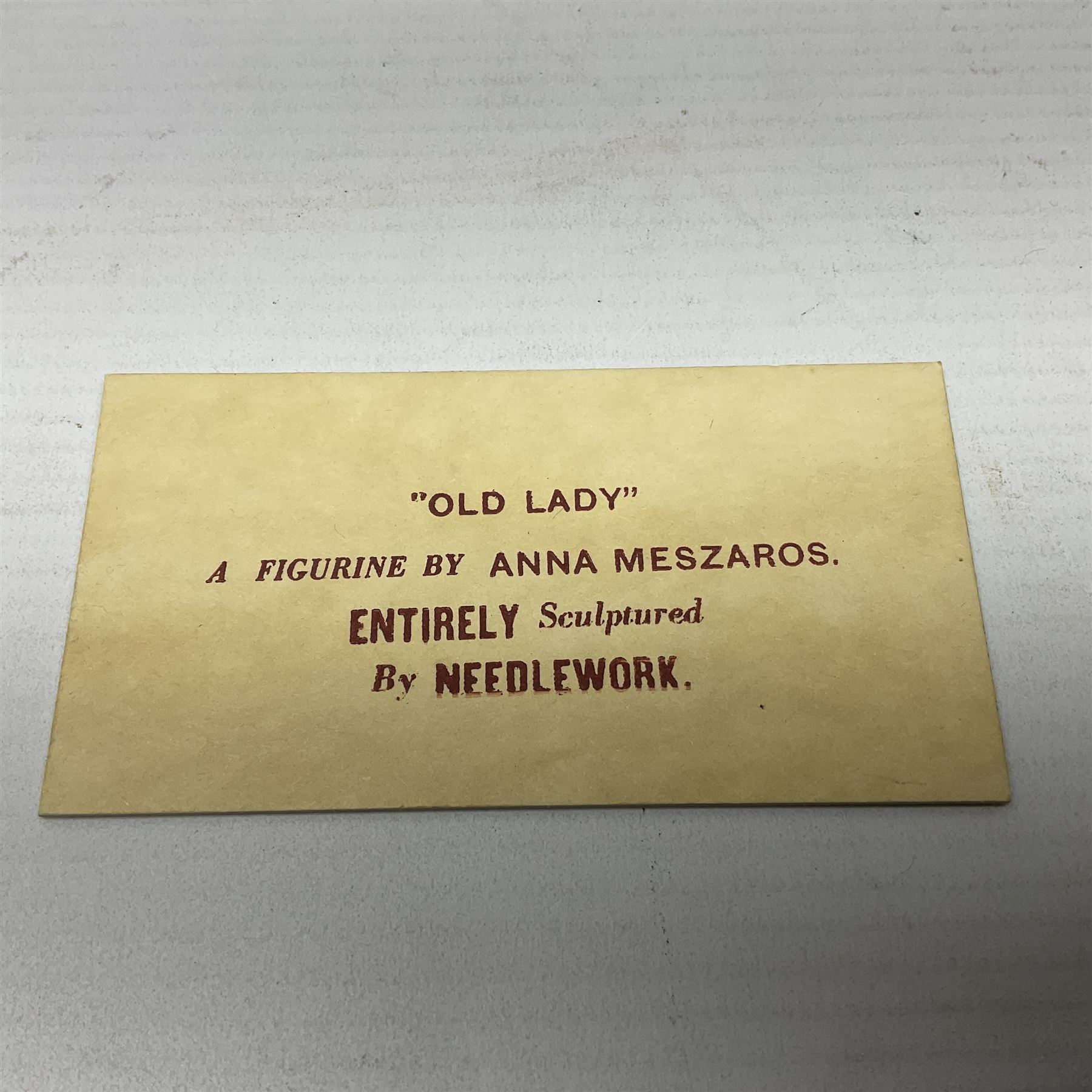 Anna Meszaros Hungary - hand made needlework figurine 'Old Lady' seated on a stool wearing a lace trimmed black/white/red floral full length dress and hat, working on a piece of lace H30cm  Auctioneer's Note: Anna Meszaros came to England from her native Hungary in 1959 to marry an English businessman she met while demonstrating her art at the 1958 Brussels Exhibition. Shortly before she left for England she was awarded the title of Folk Artist Master by the Hungarian Government. Anna was a gifted painter of mainly portraits and sculptress before starting to make her figurines which are completely hand made and unique, each with a character and expression of its own. The hands, feet and face are sculptured by layering the material and pulling the features into place with needle and thread. She died in Hull in 1998.
