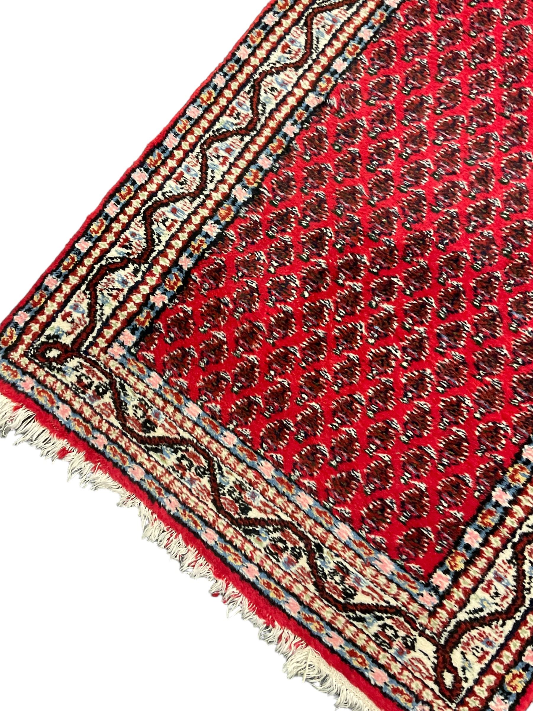 Persian design red ground runner, the field decorated with repeating Boteh motifs, five-band border (277cm x 74cm); Bokhara design red ground rug, decorated with a single row of Gul motifs (272cm x 69cm)