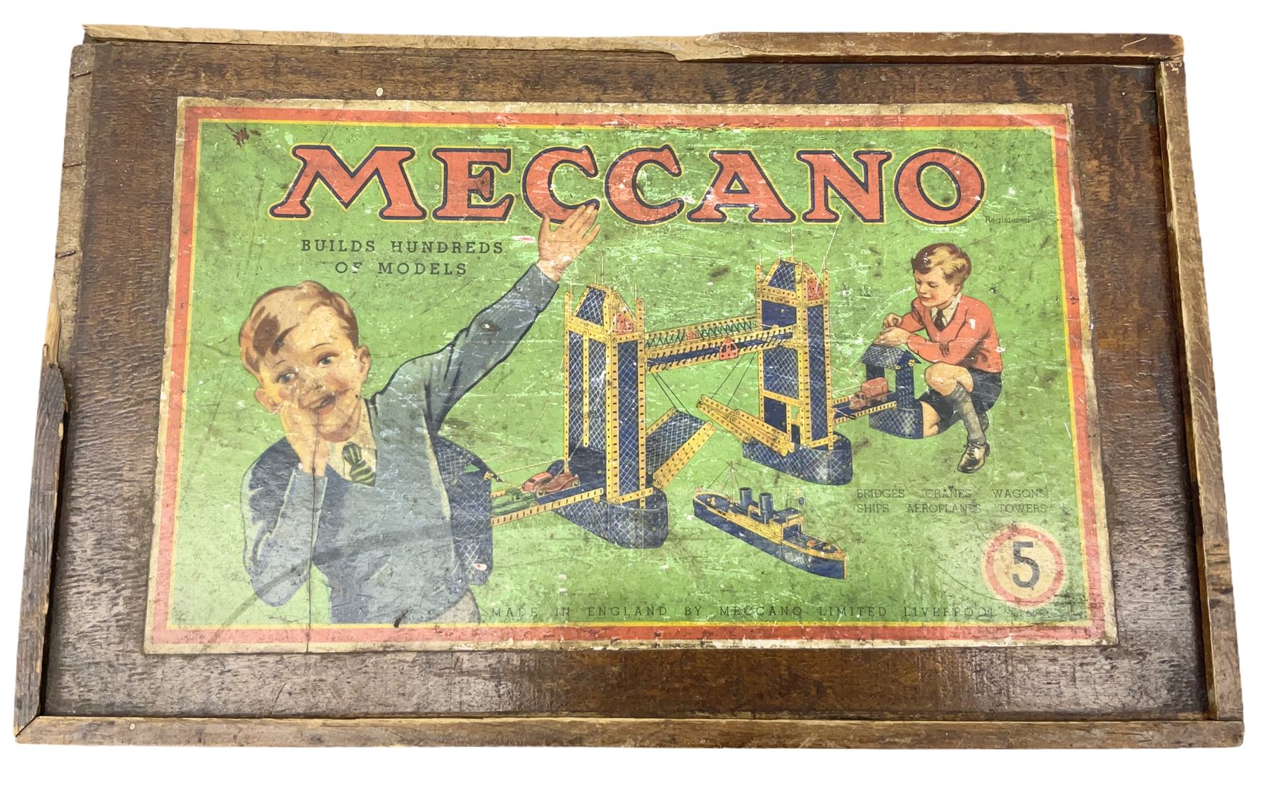 Meccano - wooden box with Set No.5 label to sliding lid, containing two lift-out trays and bottom layer of predominantly red and green sections, wheels, pulleys, rods, tyres etc, carrying handles to either end, L36cm D22.5cm H13.5cm
