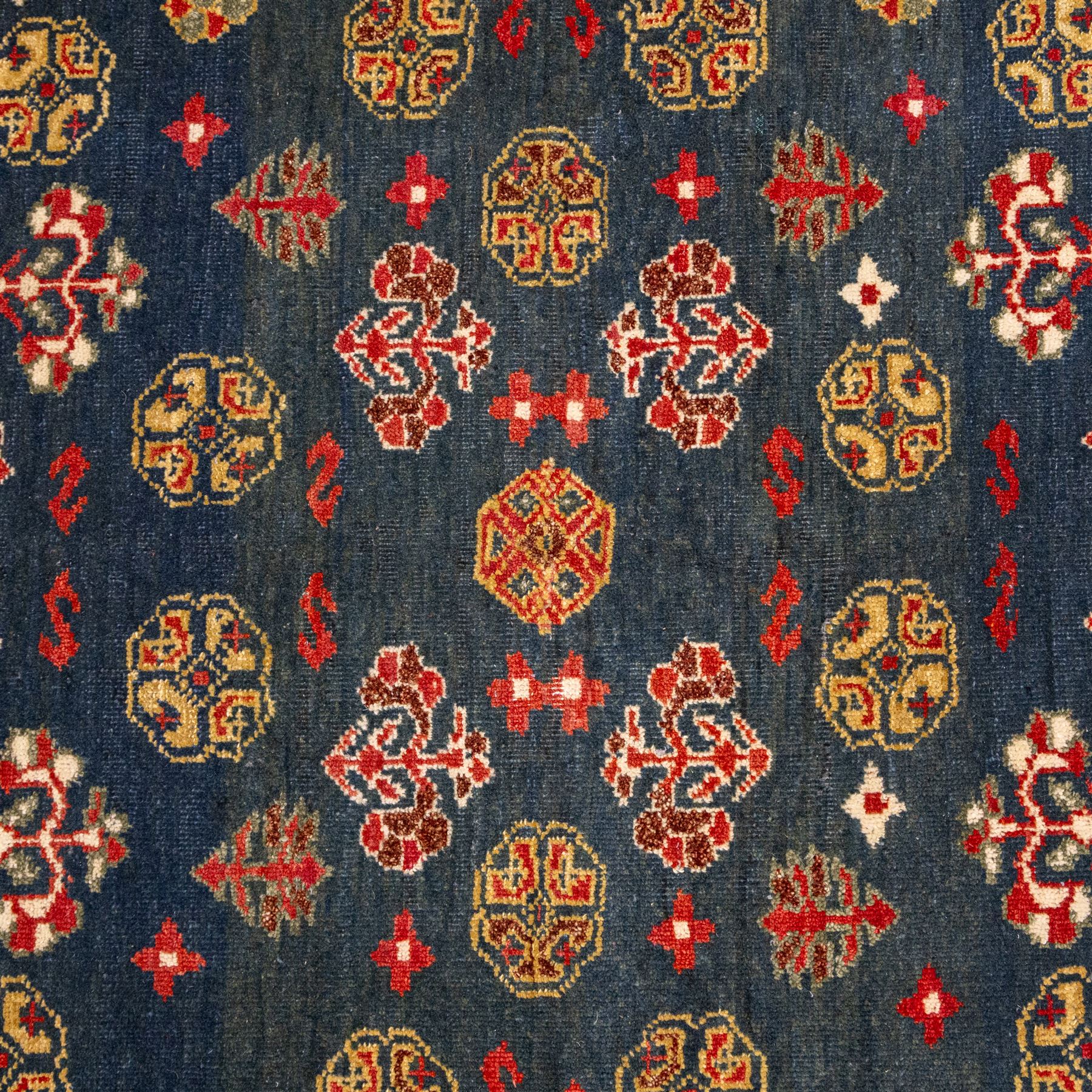 North East Persian Turkoman hand-knotted rug, deep teal blue field decorated with repeating rows of stylized octagonal guls and cruciform tribal motifs arranged in a lattice formation, enclosed composition featuring angular devices and reciprocal motifs, with cotton fringe ends