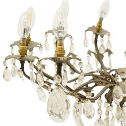 20th century Louis XV design gilt and patinated metal twelve-light chandelier, the foliate-cast baluster stem issuing scrolling acanthus branches with leaf-form drip pans, hung throughout with faceted glass pendants and lustre drops, suspended from chains beneath a foliate ceiling rose