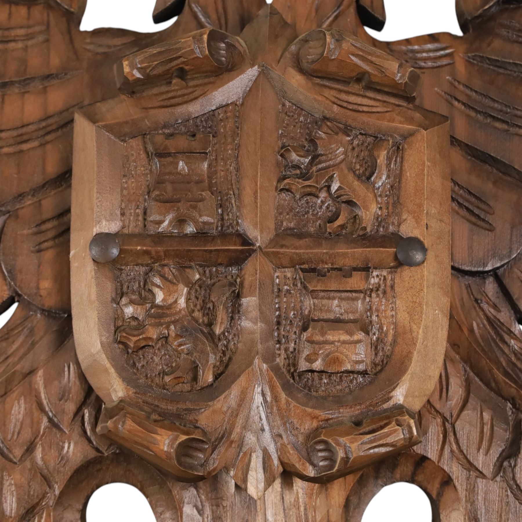 Carved wooden wall plaque, decorated with foliate scrolls, with two reproduction swords attached, together with five other wooden plaques with foliate scrolls and shields