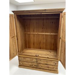 Pine wardrobe enclosed by two panelled doors and fitted with four long drawers, platform support