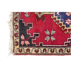 Turkish crimson ground rug, the field decorated with four hooked lozenges, trailing border with stylised flower heads 