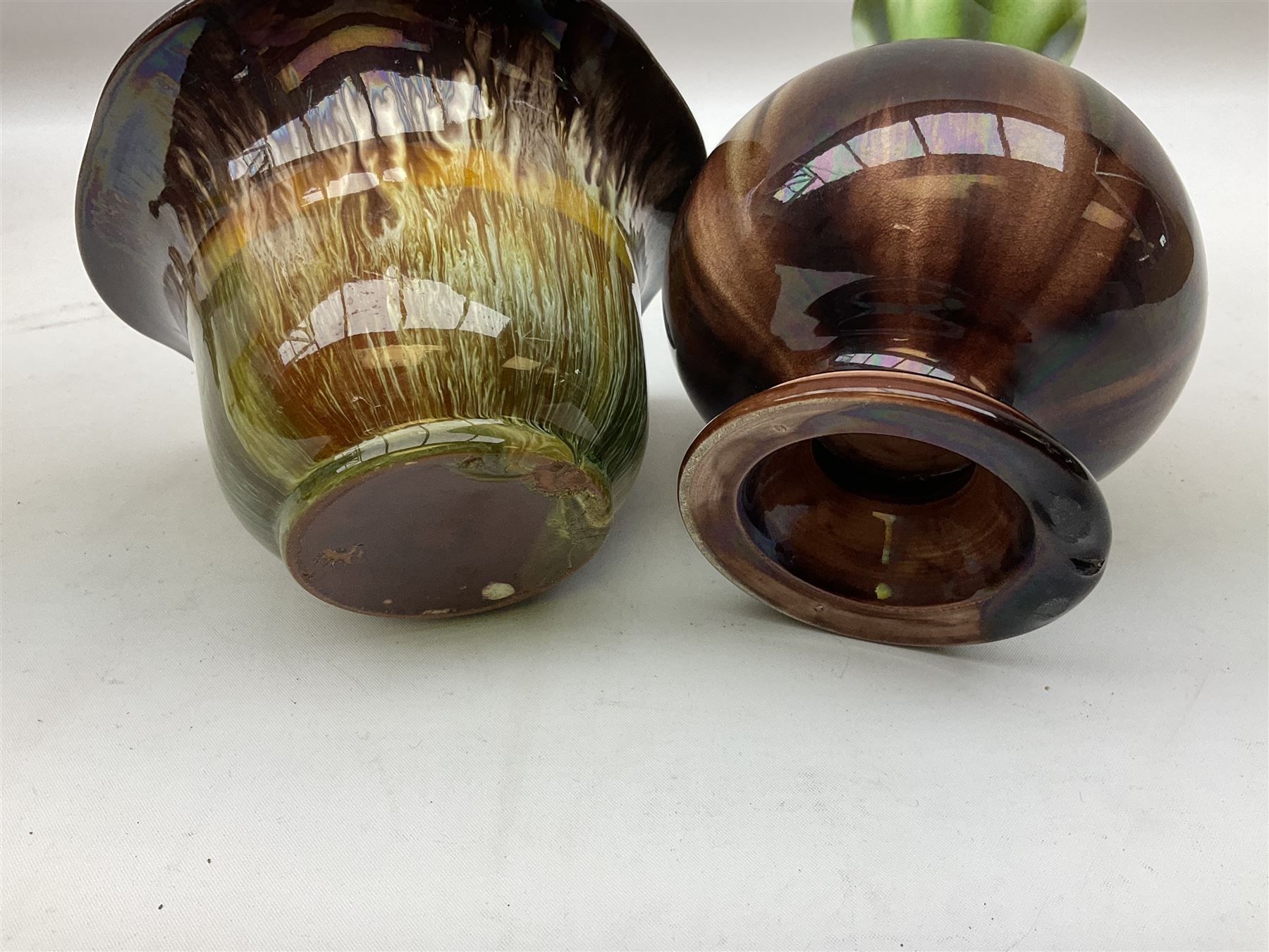 Linthorpe pottery vase with crimped rim and ovoid body, Linthorpe jug with high loop handle and crimped spout, a pair of candlesticks with a green, brown glaze and other similar pottery 