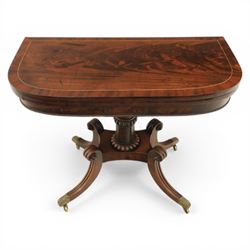 Early 19th century Regency mahogany fold over card table, the rounded rectangular top with brass line inlay enclosing green baize playing surface, crossbanded and strung exterior, with reeded edge above a gadrooned frieze, raised upon a turned column and four reeded sabre supports terminating in brass caps and castors