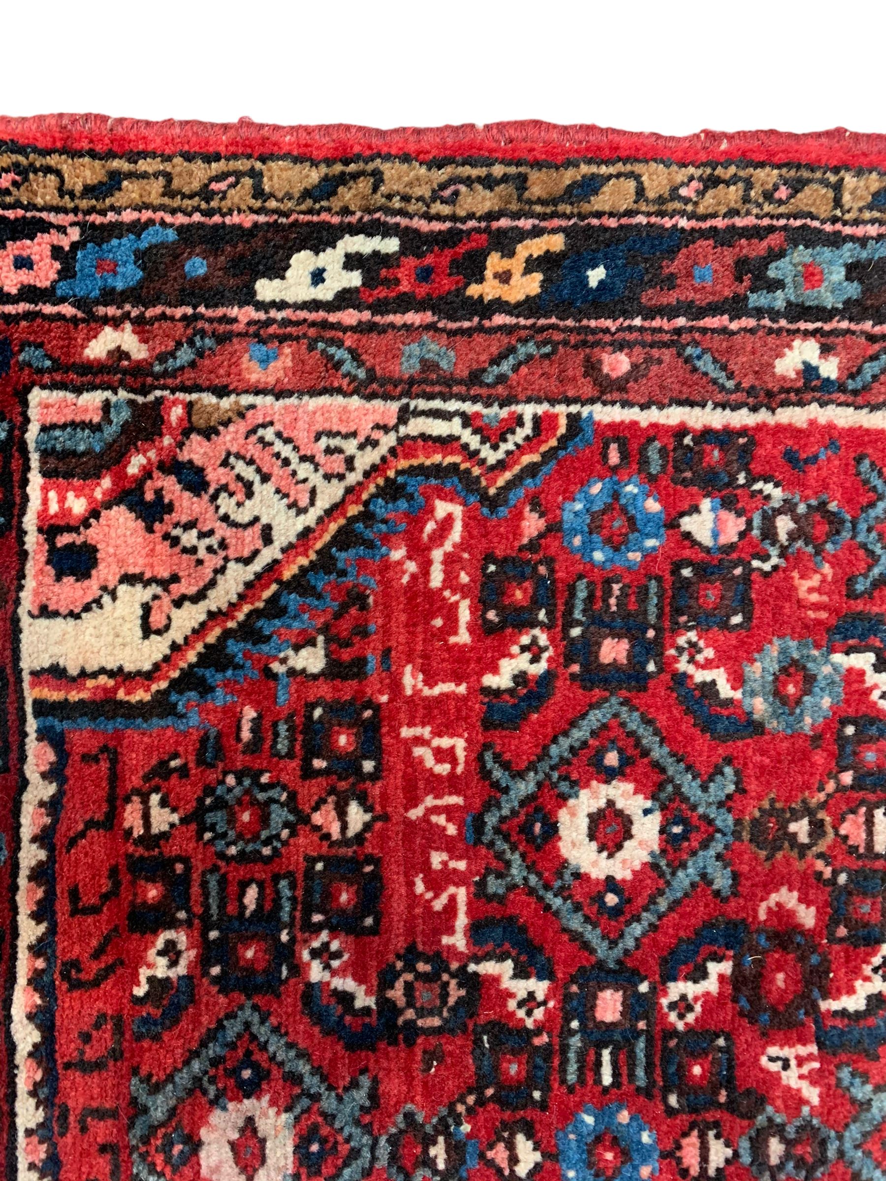 Persian crimson ground runner, the field decorated with Herati motifs,  three-band border, the main band decorated with repeating flowerheads 