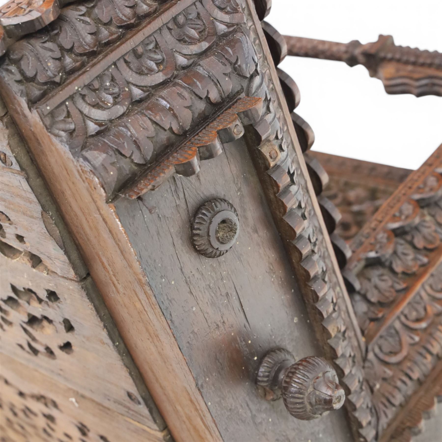 20th century Indian carved hardwood corner shelf, the tiered pagoda form with pierced and carved foliate panels centred by figural carving, supported by turned and carved columns, with shaped brackets and pendant finials