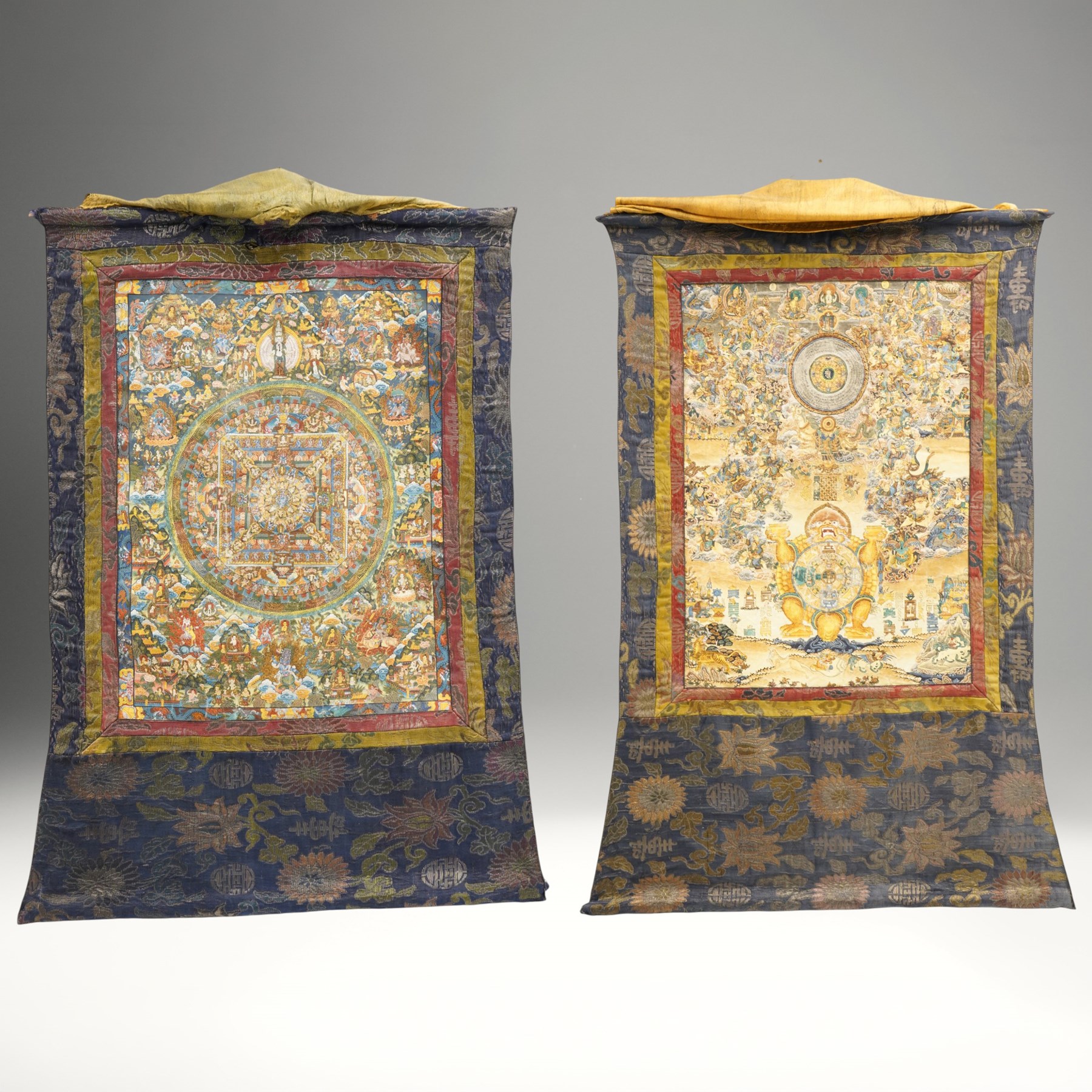 Two 19th century Tibetan Thangkas, depicting Bhavachakra or the Wheel of Life, and the other depicting a Buddhist mandala, each mounted on brocaded fabric, image sizes 64cm x 46cm and 62cm x 47cm (2)