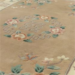 Chinese wool rug, beige ground decorated with peonies, flowering branches and butterflies, centred by a shou symbol within key pattern surround, cream border with floral sprays and double happiness motifs, cotton fringe ends