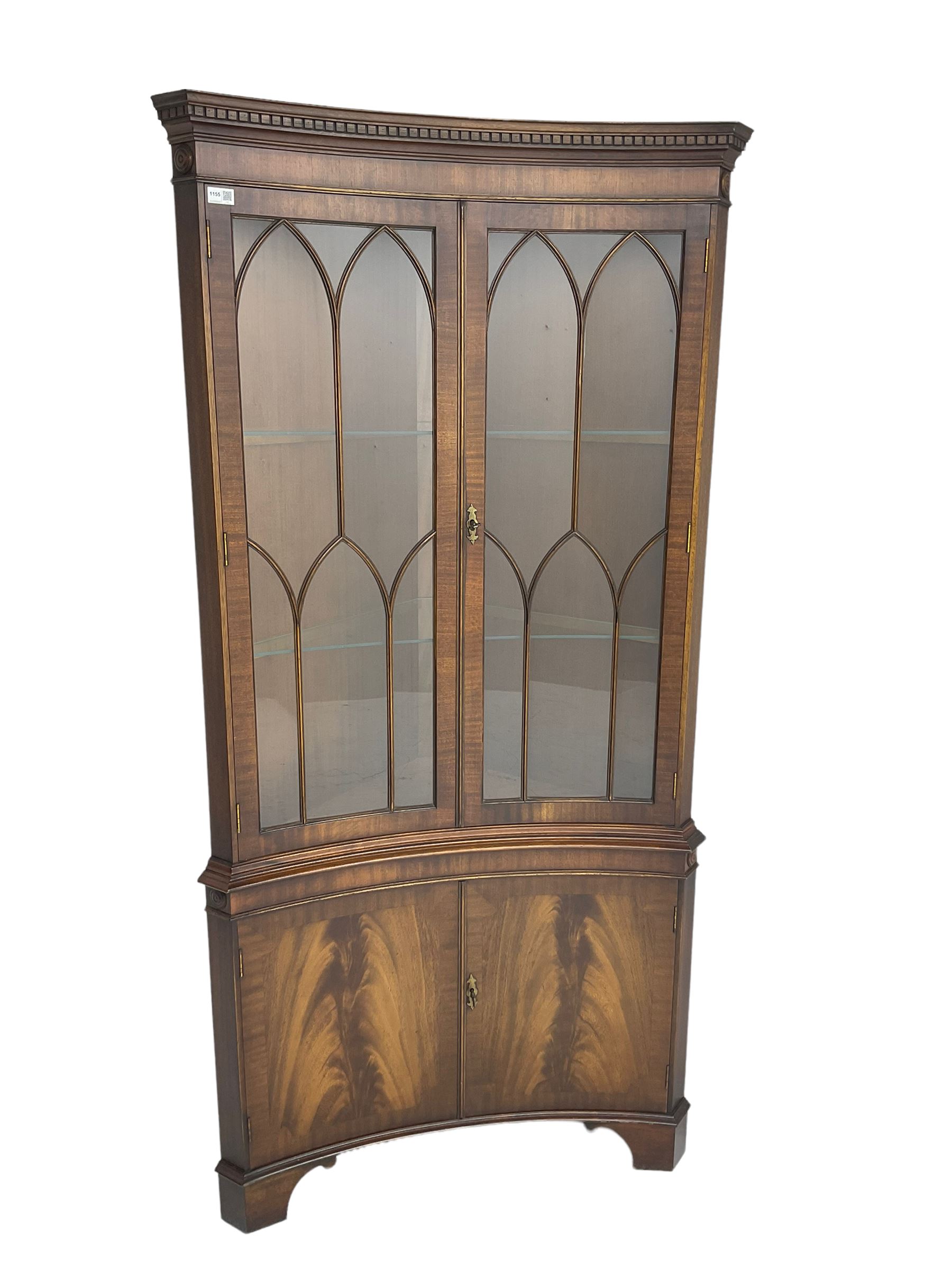 Bevan Funnell Reprodux - mahogany concave corner display cabinet, the moulded and dentil cornice over two astragal glazed doors, double cupboard below enclosed by figured doors, on bracket feet