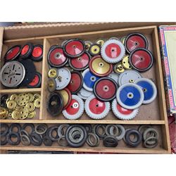 Meccano - large quantity of loose parts including various plates and strips, flanged plates, pulleys, axle rods and crank handles, wheels and tyres, gear wheels, brackets, nuts & bolts, various manuals; predominantly red and green; some in compartmentalised wooden trays