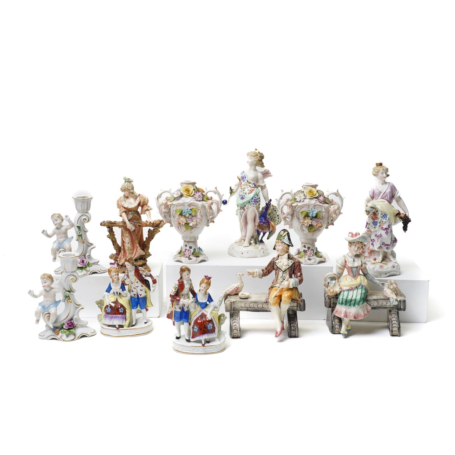 Collection of German and continental porcelain figures, including a figure of Juno with peacock, two figures feeding birds on benches, cherub candlesticks, and others