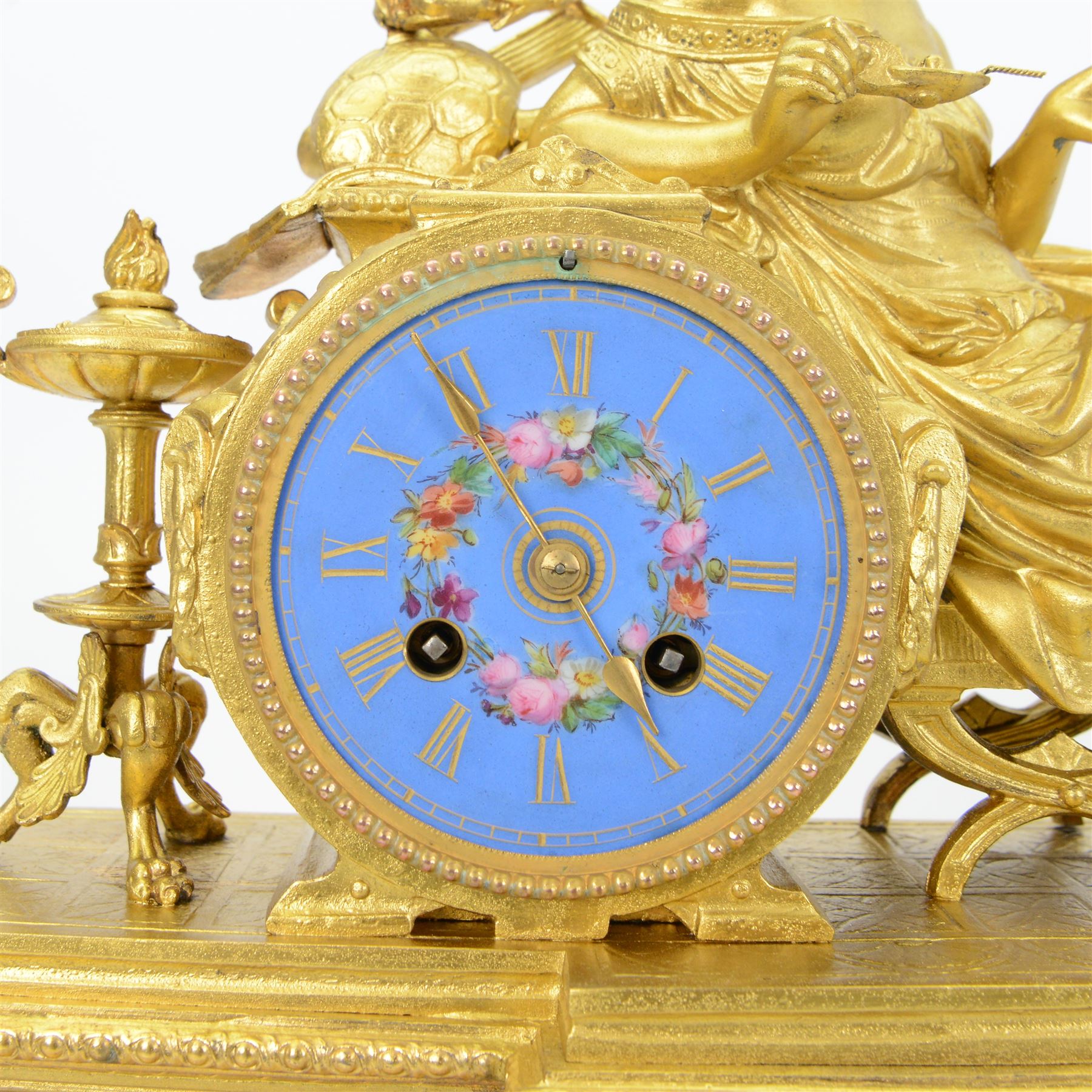 French- Napoleon III porcelain inset 8-day figural clock in a gilt case c1870, drum housed movement resting on a rectangular plinth with light blue porcelain panels each painted with different classical images and depictions from antiquity, conforming dial with a garland of flowers to the centre, gilt Roman numerals, minute track and brass spade hands, with a seated figure of a classical maiden reading a book, mounted on a matching gesso base with a velvet padded top, Parisian countwheel striking twin train movement, striking the hours and half hours on a bell. With a contemporary ebonised base and oval glass dome. With pendulum.
