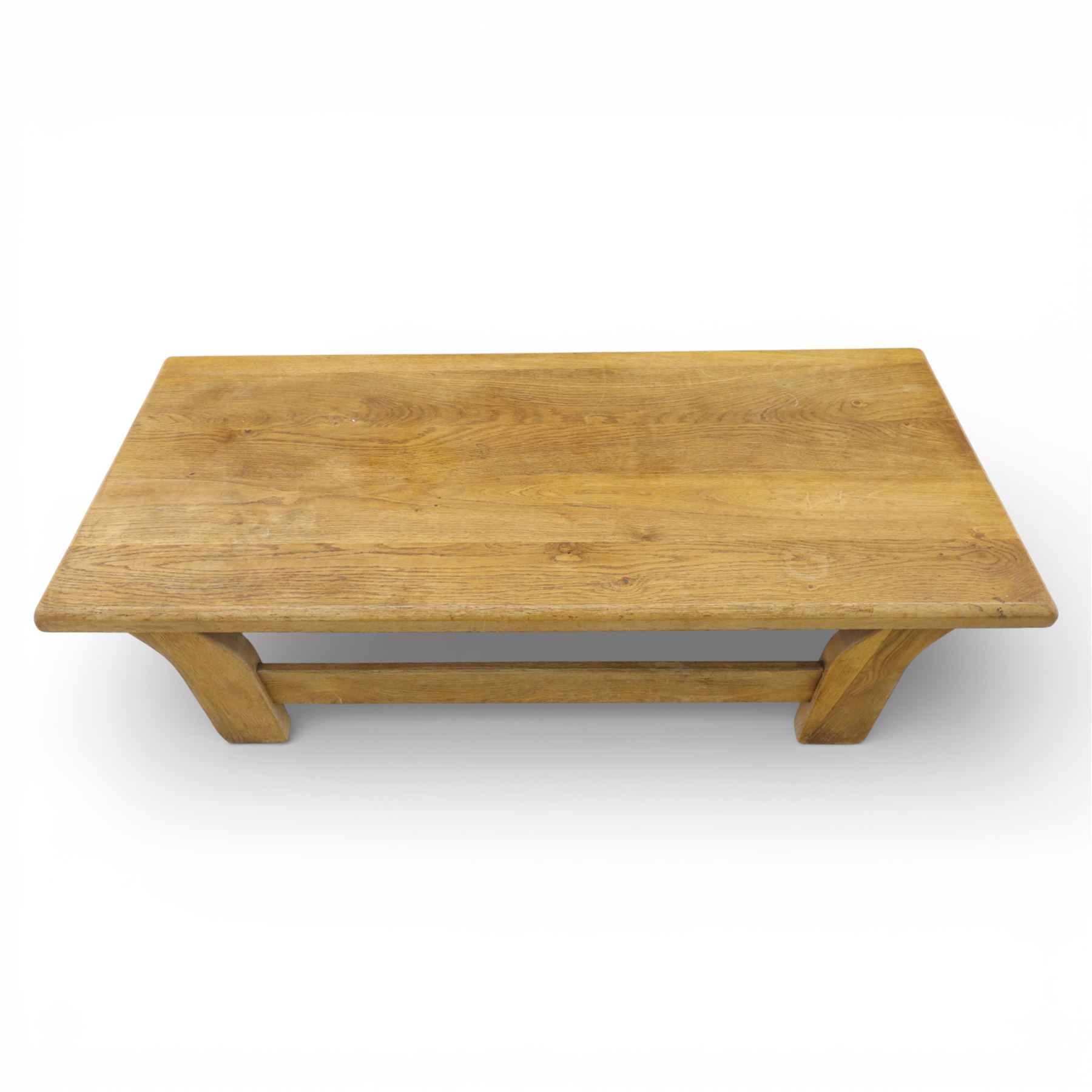 Modern oak coffee table, rectangular solid top with softly rounded edges, raised on shaped slab end supports united by a full-width stretcher