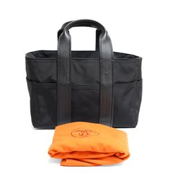 Hermès - Acapulco PM tote bag in black Toile Chevron canvas with black leather trim, the rectangular body with twin flat handles incorporating stitched H details, top zip fastening and eight exterior slip pockets, opening to a black nylon-lined interior with zip pocket, palladium-tone hardware, stamped Hermès Paris Made in France, with original Hermes dust bag