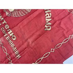1970s Soviet banner printed in gold on a red ground, roughly translates as 'Transferable Banner - To the winner in the Socialist Competition' and 'Work Study Live by Communism' verso; wreath of wheat ears to either side; tassels on three sides 110 x 155cm