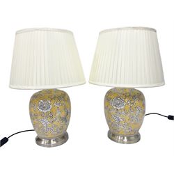 Pair of table lamps of baluster form, decorated with a stylised floral design on a yellow ground, on brushed chrome pedestals, including shades H53cm