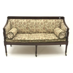  Regency mahogany framed settee, upholstered in a beige ground floral patterned fabric, turned supports on brass castors, W159cm  