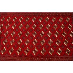 Turkmen hand-knotted carpet, deep crimson ground field, with an all-over lattice of repeating diamond guls, each enclosing angular cruiform motifs, and stylized tribal devices, interspersed with smaller geometric ornaments, main border decorated with repeating geometric motifs and stylized tribal elements, flanked by narrow guard stripes, with cotton fringe ends 