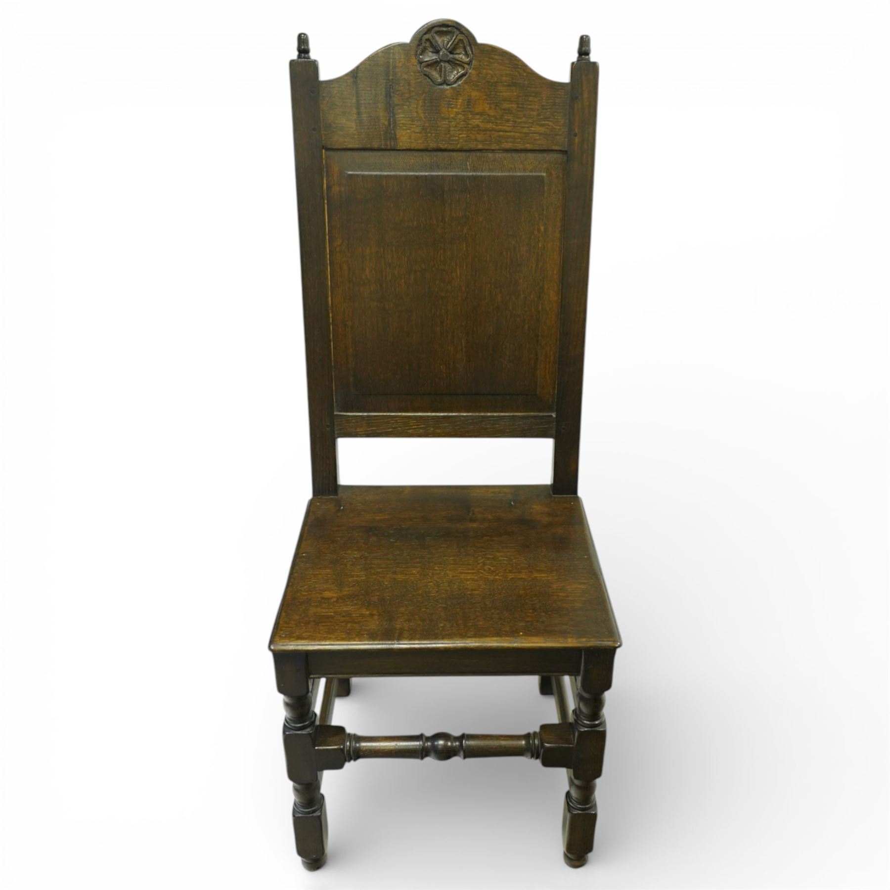 20th century oak refectory style dining table and eight chairs (6 + 2), rectangular top on two large carved baluster pedestal supports with leaf decoration, on splayed trestle bases joined by a stretcher, with eight matching oak dining chairs, each with Yorkshire rose carved cresting rail, panel back and solid seat, raised on turned supports united by stretchers