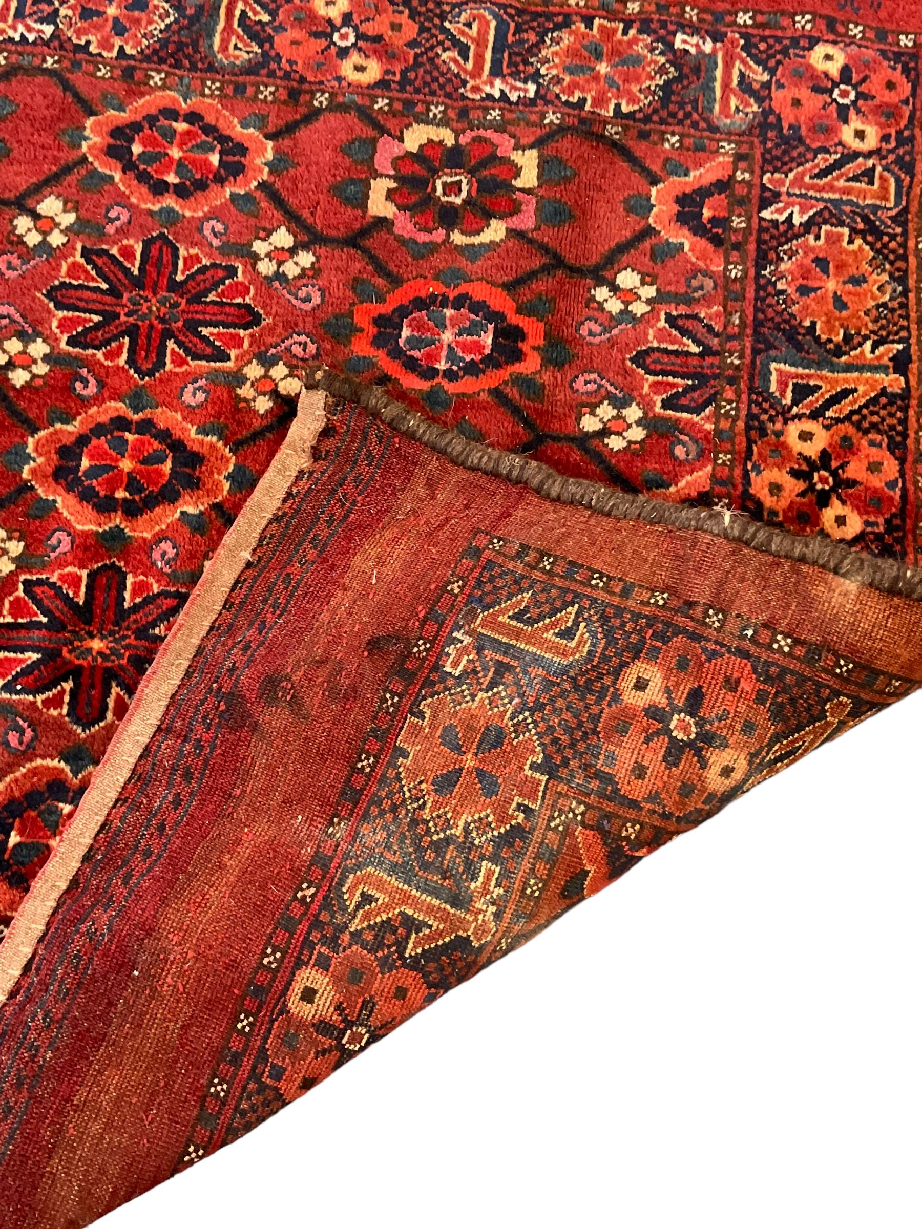 Persian red ground rug, the field decorated with lattice pattern and flowerhead, repeating border decorated with flower heads and leaf motifs
