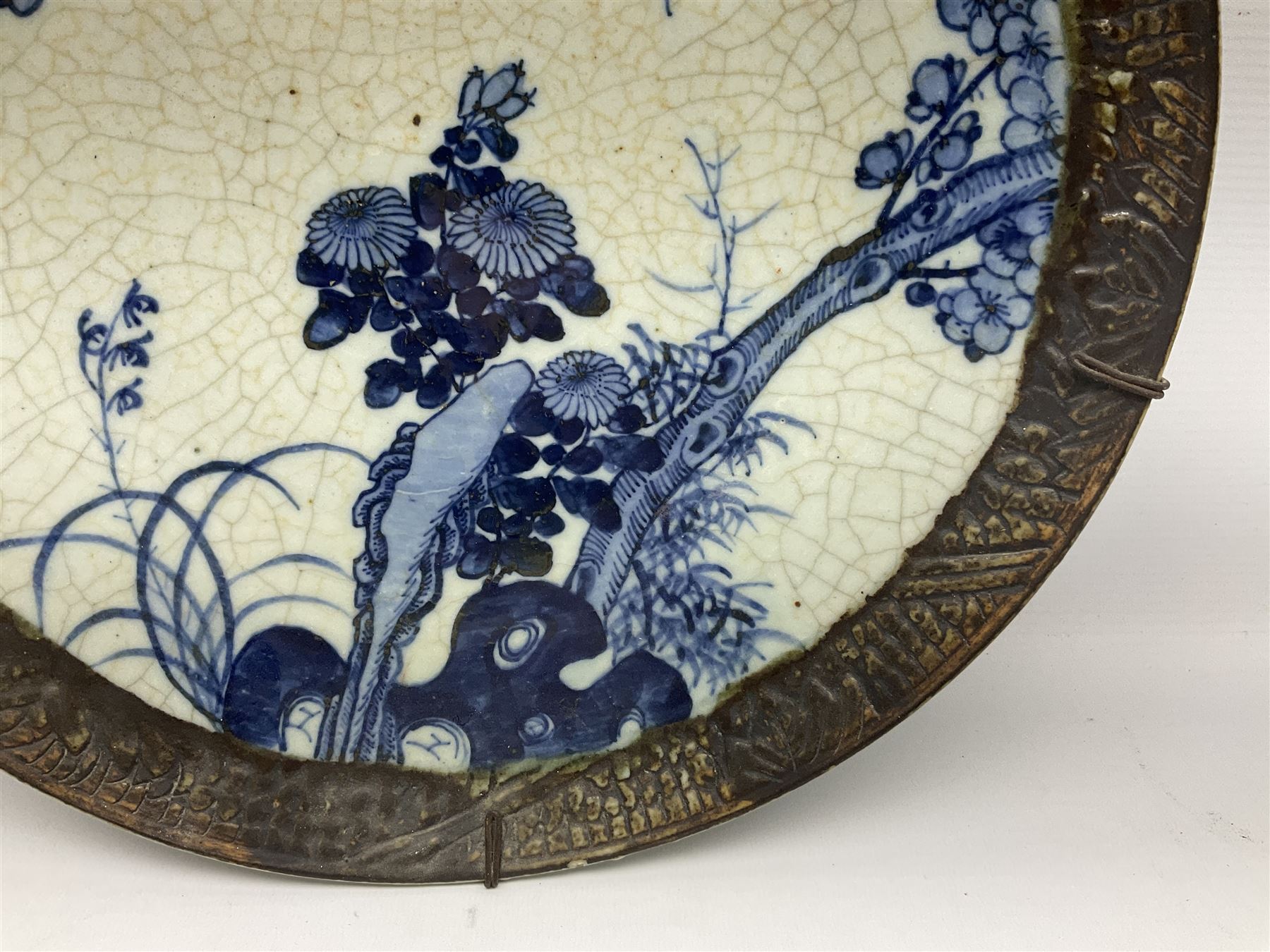 20th century Chinese blue and white crackle glaze charger, decorated with peonies, prunus blossom, and rockwork, within simulated bronze border, with character mark verso, D34cm