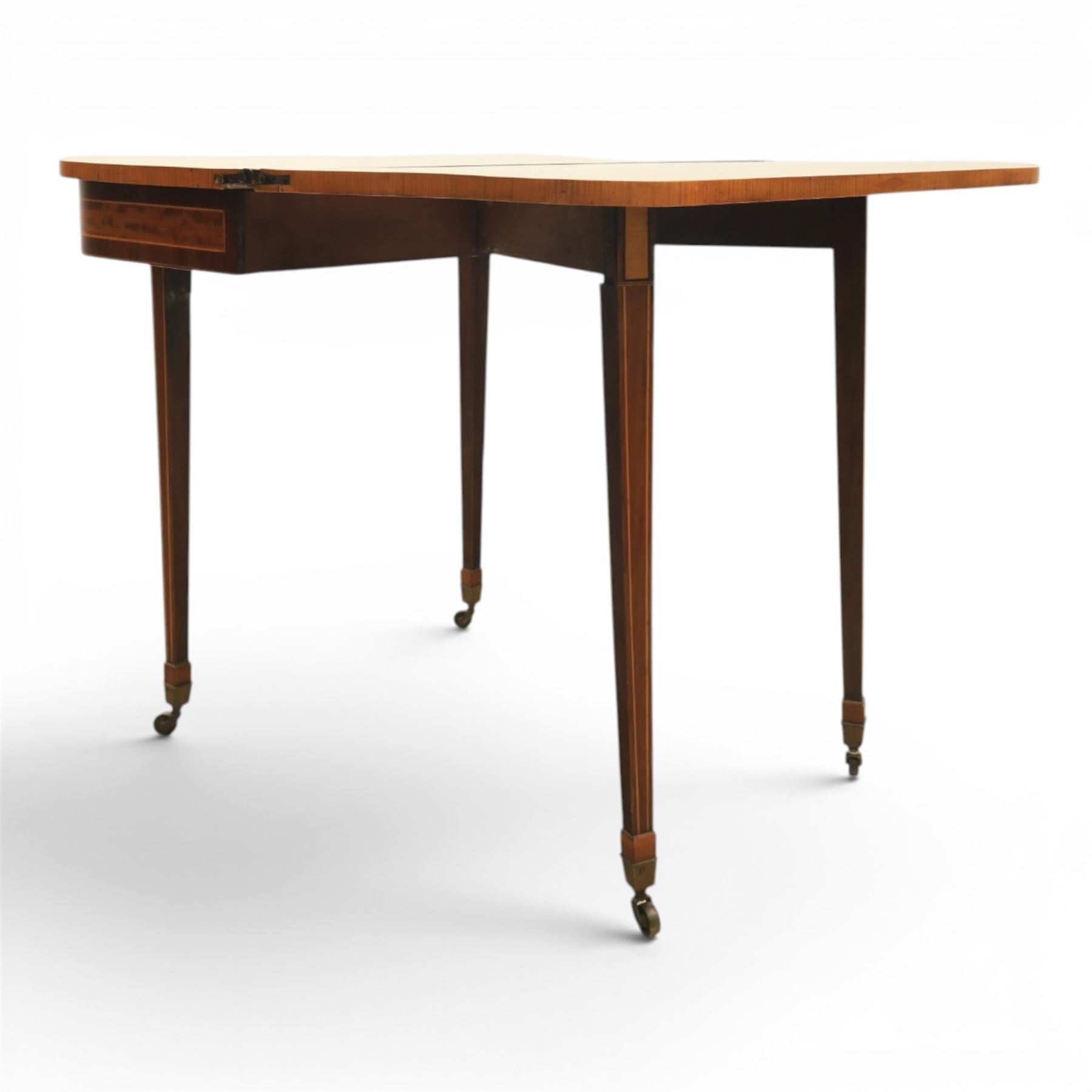 Regency mahogany fold-over tea table, rounded rectangular top with gateleg action, inlaid and crossbanded frieze, raised on squared tapering supports on brass castors