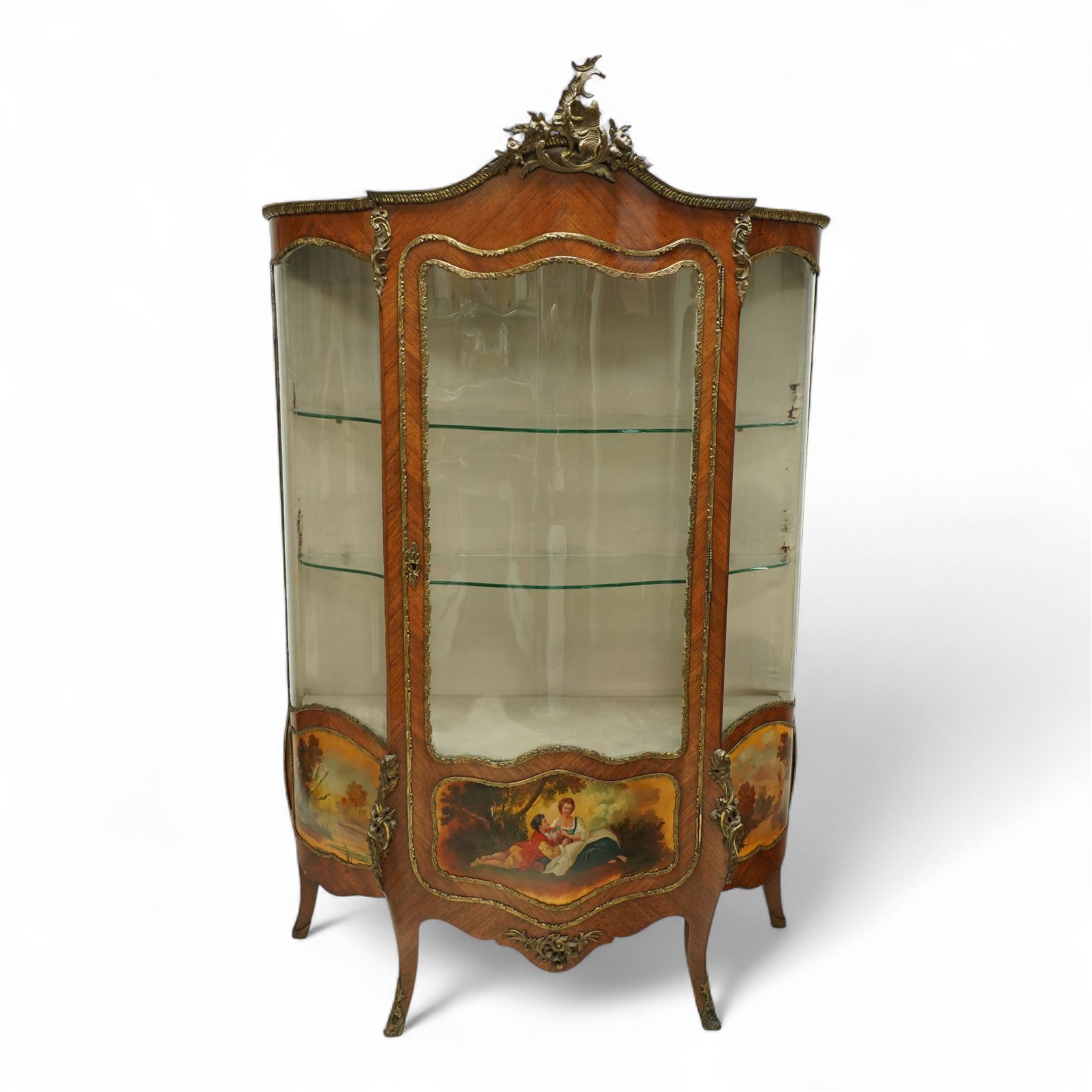 Louis XV revival kingwood Vernis-Martin serpentine fronted vitrine cabinet, arched top with gilt brass foliate mounts, glazed door with two shelves above three painted panels, depicting pastoral scenes, supported on out-swept cabriole legs with gilt brass mounts and sabots.
