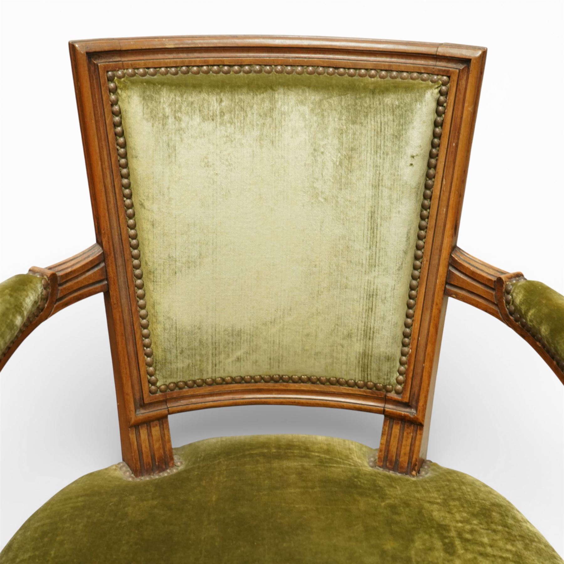 French Louis XVI style walnut armchairs, rectangular upholstered backs with nailhead trim, padded seats upholstered en suite, out-swept arms with upholstered pads, fluted supports with carved rosettes to the knees, on turned and fluted tapering legs