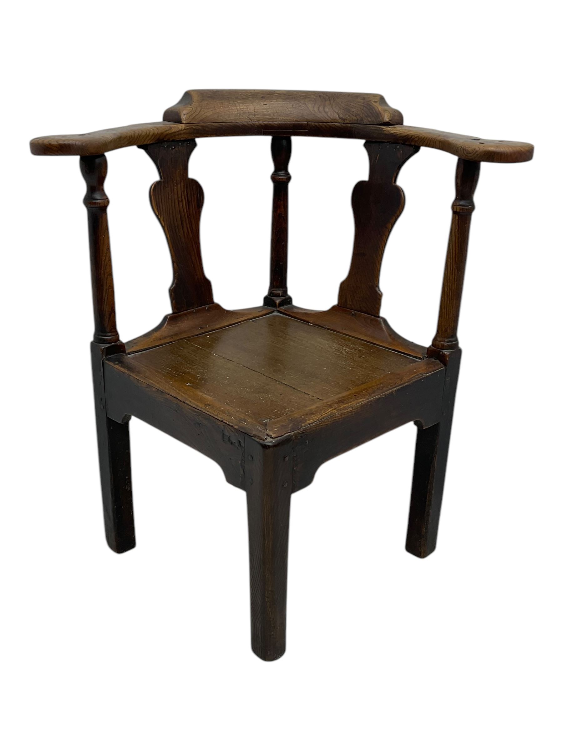 18th century oak corner elbow chair, the shaped cresting rail terminating to swept arm rests, supported by turned columns and vase-shaped splats, over square plank seat, raised on square-section supports