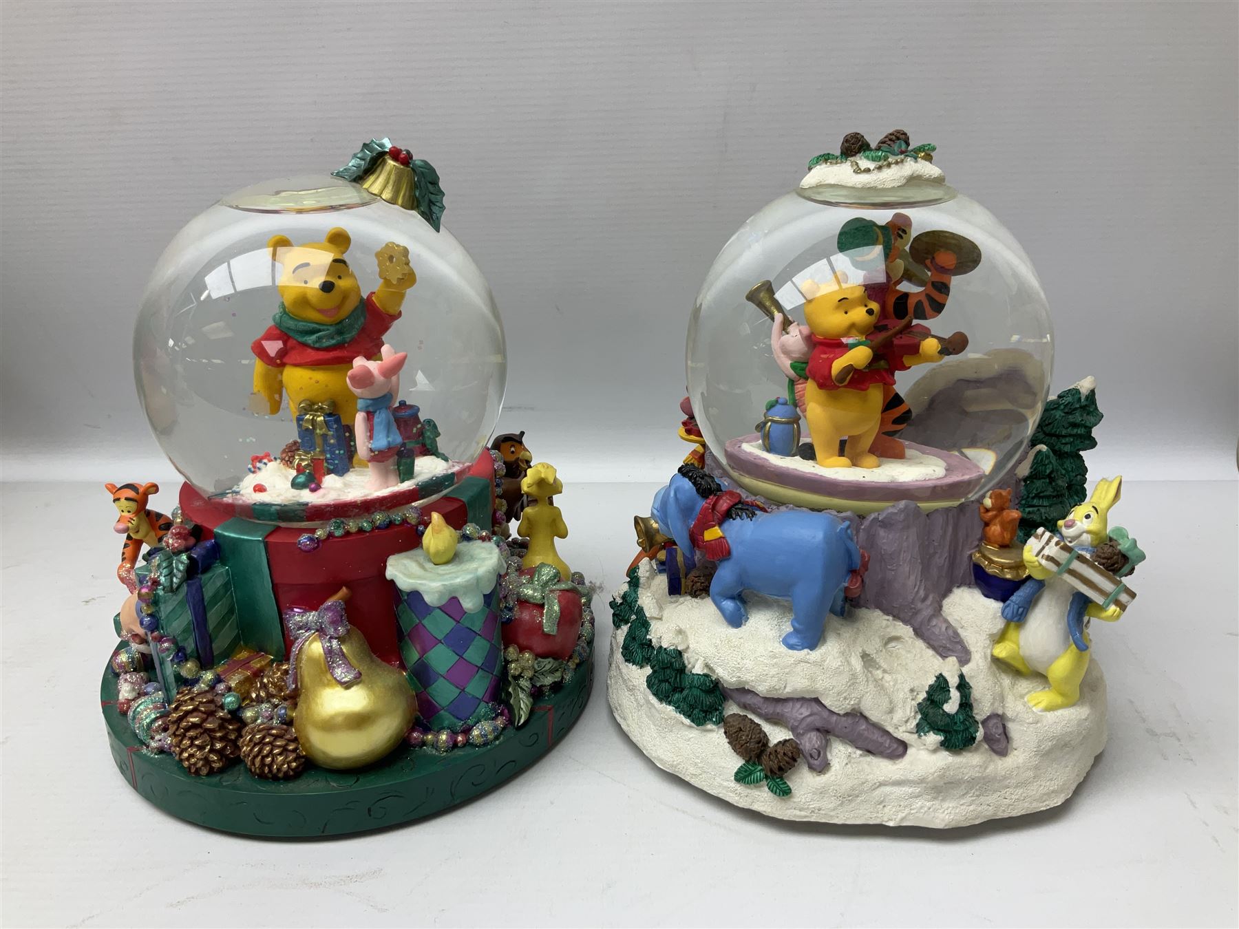 Six Disney Winnie the Pooh Christmas snow globes, comprising large Mr Christmas Holiday Snowfall, An Enchanted Christmas, It's A Small World Christmas 1994,  Tree Trimming, 1995 Christmas At Our House and Christmas Band Concert, together with Mr Christmas Holiday Go Round, all with boxes (7)