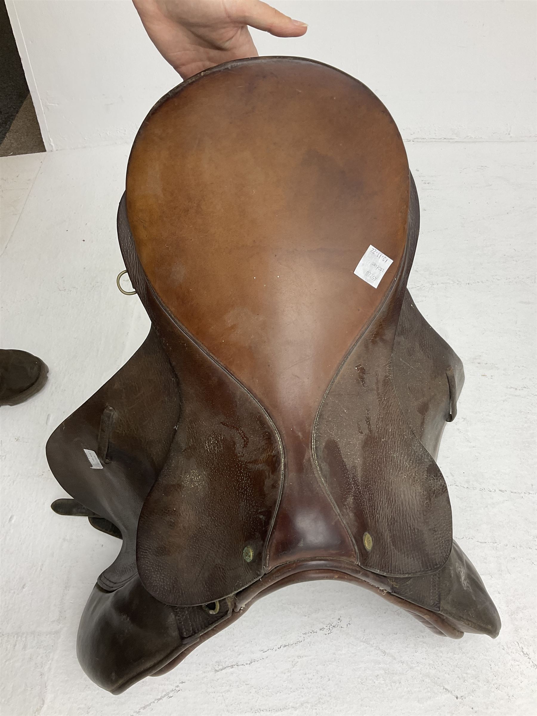 Collection of nine saddles, mainly havana leather to include a racing saddle and a Goodwin saddle, some with stirrups and leathers 