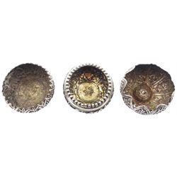 Three Eastern silver open salts, each of circular form and decorated in relief, two examples decorated with animals in a jungle setting, the third with foliate panels, approximate total weight 3.12 ozt (97.2 grams)