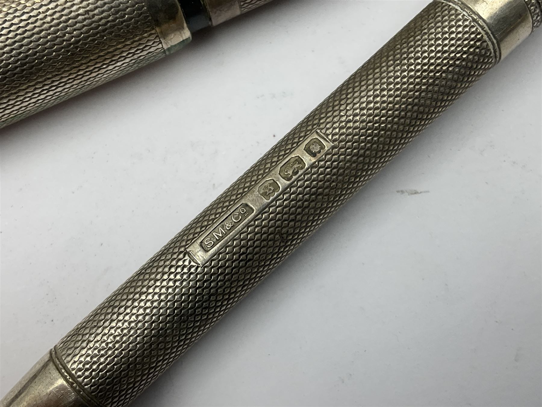 Three parker fountain pens, one example with 14ct gold plated cap and personal engraving, in Parker 51 box, together with a silver Sampson Mordan Everpoint propelling pencil with personal engraving and a silver cased fountain pen with 14ct gold nib and a souvenir bronze Dollfus-Mieg medallion, awarded to John G Sedorski, in fitted case 