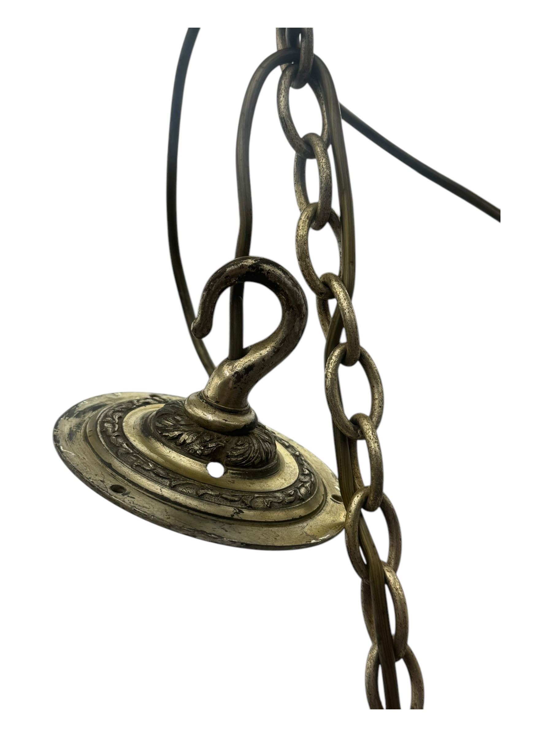 Pair of mid-20th century brass chandeliers, each with cast foliate and scroll decorated central body, issuing six scrolling arms with circular drip pans and bulb holders, suspended from integral ceiling loops
