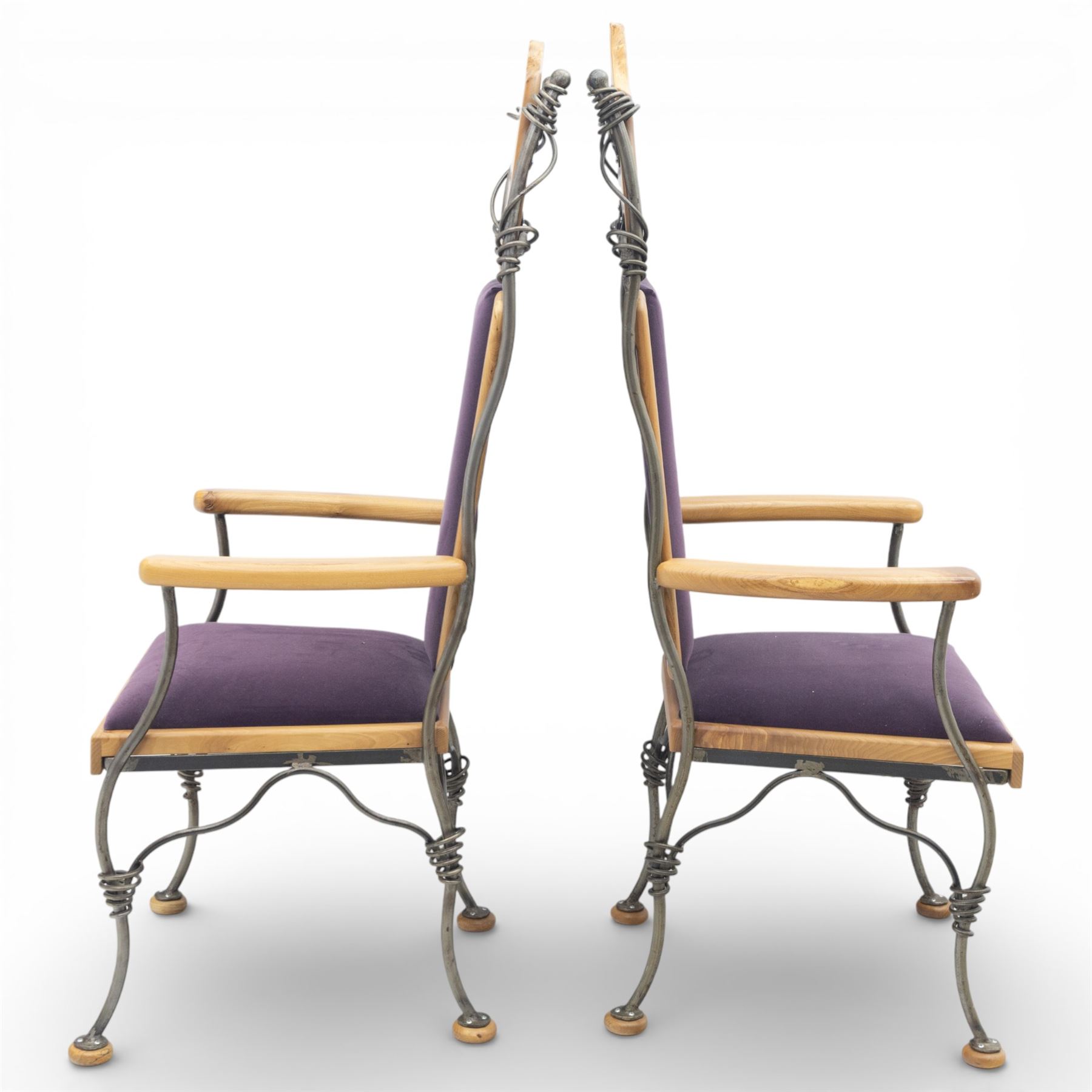 Paul Hodgkiss Designs of Glasgow - contemporary shaped elm dining table with wrought iron base; with set ten (8+2) matching high-back dining chairs, table of organic form above an elaborate wrought iron supports, with central elm stretcher, the chairs with en suite with matching wrought iron work burred elm headrest, purple velour upholstery with drop in seat     

Table: W 102cm, L 243cm, H 74cm
Chairs: W 56cm, D 52cm, H 130cm